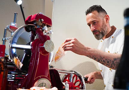 Nico, Inhaber des Eiskaffee La Dolce Lucania in Feuchtwangen und Herrieden, bei der Zubereitung italienischer Spezialitäten an der Aufschnittmaschine